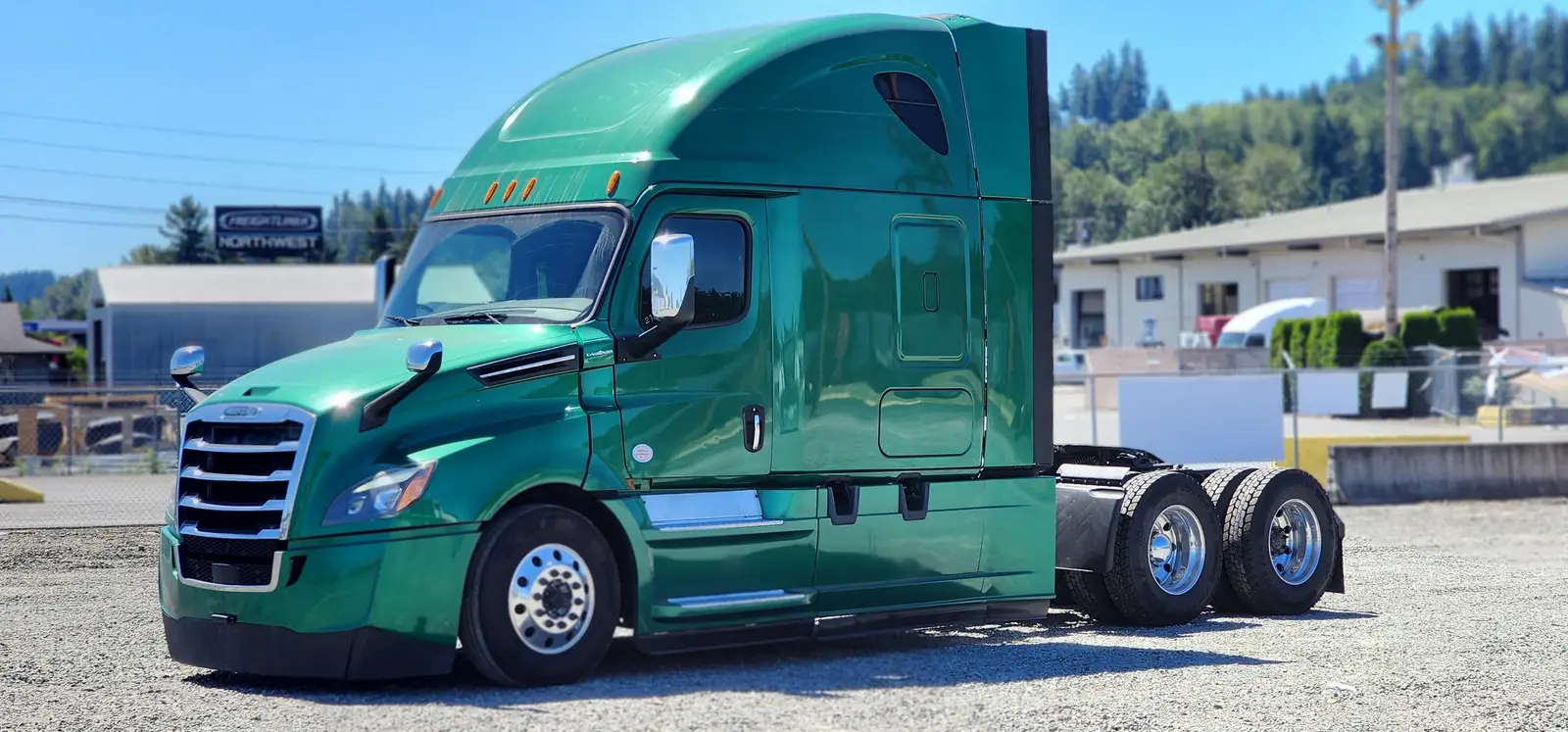Green Freightliner Cascadia sleeper tractor with no trailer attached, parked on gravel